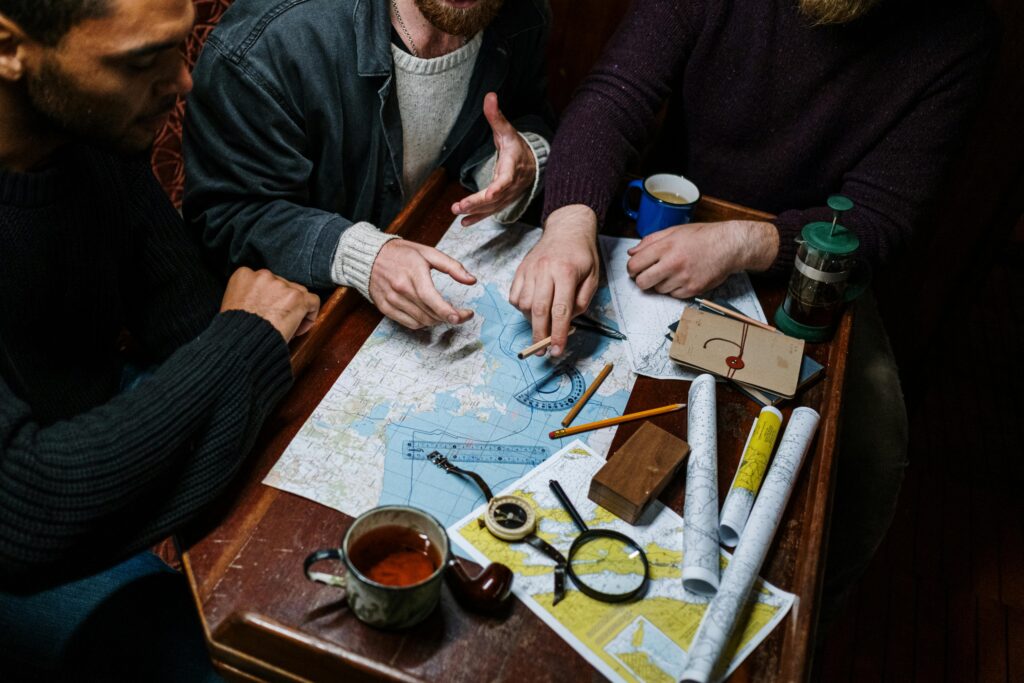 Group of adults planning a nautical adventure using maps and tools. Overhead view.