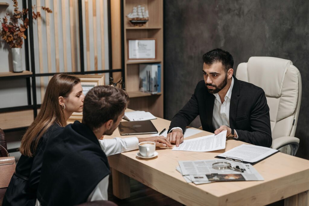 Lawyer discussing legal documents with clients at office desk.